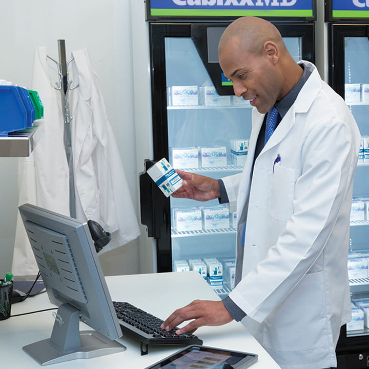 Man at a computer holding pharmaceuticals