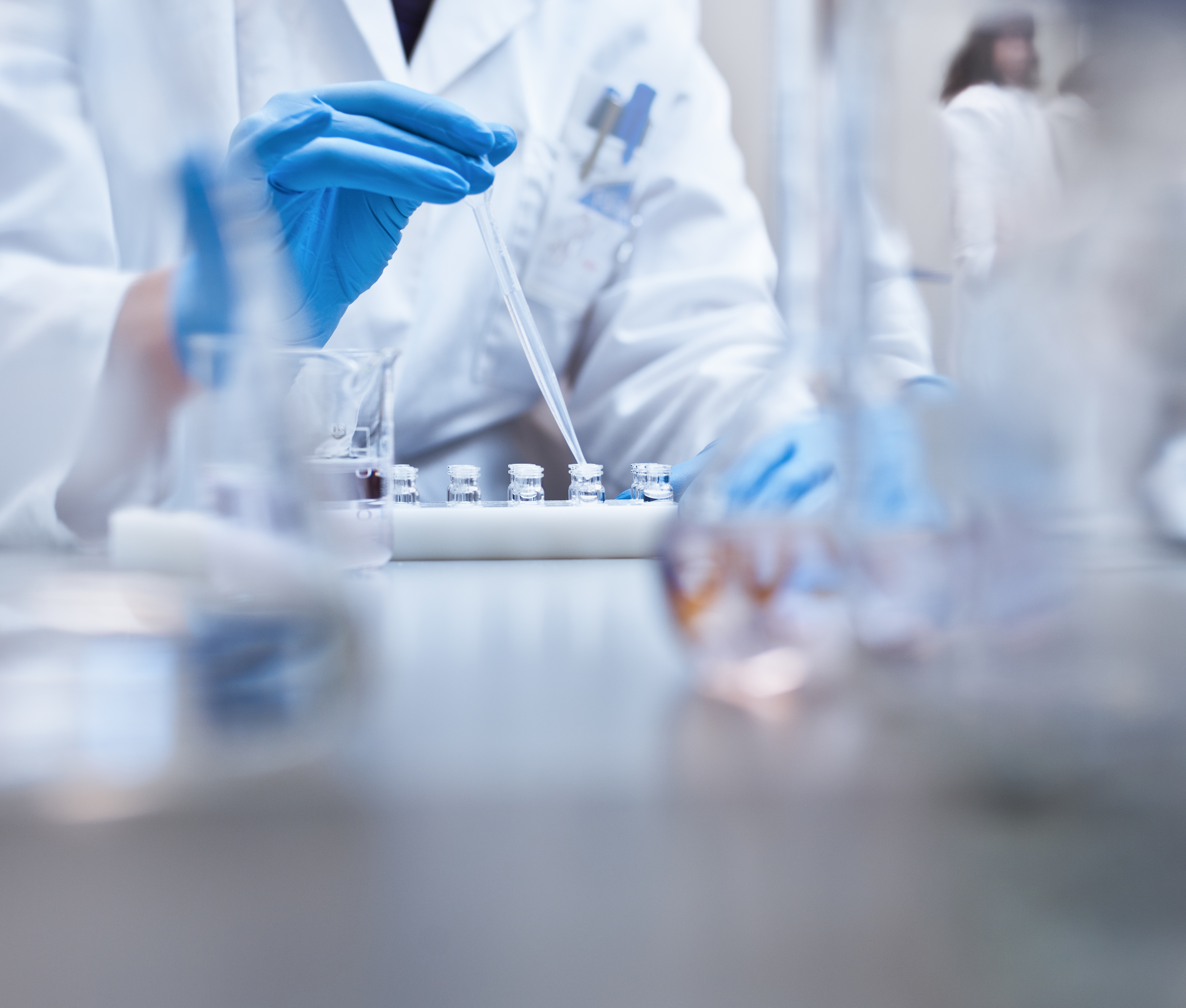 Lab technician conducting testing with vials and dropper